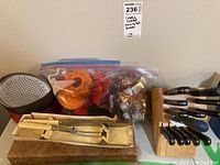 Complete view of lot showing cookie cutters in ziplock bags, round metal grater, carving tools in wooden box, and wooden knife block with multiple kitchen knives
