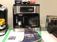 Front view of DeLonghi coffee and espresso machine with portafilter attached and glass carafe