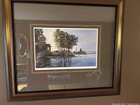 Front view of the framed and matted print showing the lakeside scene, cabin, and misty background.