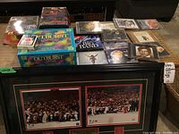 Wide view of the collection showing framed Team Canada 2010 hockey photos and pins, Spiderman toys in sealed boxes, several music CDs, Outburst Junior board game box, and Bicycle playing cards.