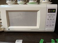 Front view of the white GE microwave oven showing the door, mesh screen window, and turntable indication.