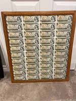 Front view of oak-tone wooden frame with sheet of Canadian one dollar bills behind glass