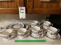 Full view of the set including teacups on saucers, dessert plates, and platter showing matching floral design and gold trim.