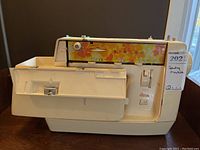 Side view of Singer Genie sewing machine showing floral graphic control panel and front access panel.
