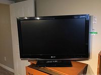 Black Sharp Aquos 42-inch LCD TV on wooden surface with remote on base