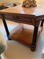 Side and close-up view of one wood end table showing detailed drawer front, black legs with gold accents, and lower shelf.