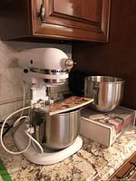 Front view of white KitchenAid Heavy Duty bowl-lift stand mixer with stainless steel bowl attached on granite countertop.