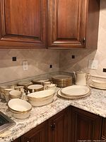 Corner countertop view of full dinnerware set including plates, cups, bowls, platters, coffee pot, gravy boat