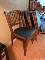 Photo showing front chair upright with three chairs folded and leaning against wall.