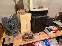 View of Kodak Carousel 800 projector in box with adjacent projector equipment and film boxes on table.