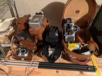 Overview of all vintage movie and film cameras, tripods, film boxes and accessories on wooden surface.
