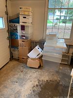 Overall stack of plastic storage totes and cardboard boxes arranged near a garage wall and window.