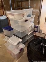 Stacked plastic storage totes of different sizes and colors with various lids.