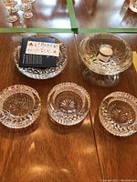 Top view of four Waterford crystal ashtrays and one tea light candle holder arranged on wooden surface.