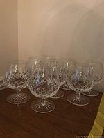 Eight Waterford crystal brandy snifters displayed on wooden surface