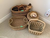 Overview of five assorted woven baskets in different shapes and sizes on carpeted floor