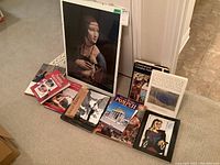 Photo showing eight art and history books arranged in a row with one unframed print leaning against a door.