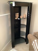 Front angled view of tall dark wood open front cabinet with smoked glass shelves, showing four shelves and wood top and legs.