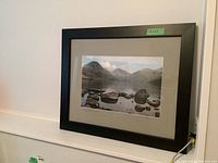 Framed print hung on a wall showing a landscape photo with black frame and neutral mat.