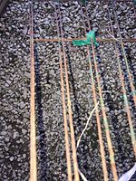 Photo showing small metal garden trellises with rust on a gravel surface.