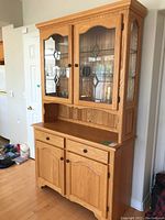 Front view of the oak buffet hutch showing leaded glass doors and bottom storage compartments.