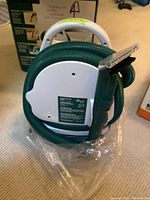 Photo of the Little Green Machine cleaner showing the hose and handle in green and white colors.