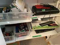 Shelf with stacked boxes and containers holding various office supplies and the Kaiser Hobby Cut 2 safety trimmer box with the Epson scanner on top.