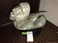 Full side view of abstract soapstone sculpture on black rotating base