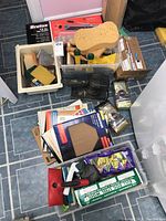 Photo showing a collection of painting and sanding tools, including brushes, sponges, steel wool, sanding papers, a Craftsman orbital sander, and a green metal mitre box.