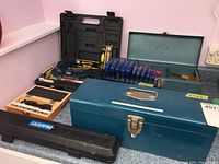 Overview of toolboxes, grip clamps, router bits box, and tool cases on counter.