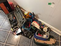 Overview of various tools including power tools, gas cylinders, containers, and accessories arranged on the floor.