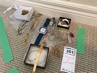 Full view of lot including various costume jewelry pieces and three wristwatches arranged on carpet.