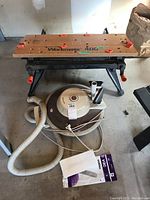 Overview photo showing Workmate 400 bench on top and vintage Baycrest vacuum cleaner on the floor with hose and cord visible