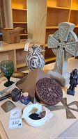 Wide view of multiple Celtic and pagan decor items on a table including the large Celtic cross statue, pentacle plaque, vase, goblet, small statues, ankh symbol, and other items.