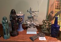 Diana archer statue, Egyptian figurines, blue goblet with pentagram, metal vase with figures holding feathers, cobalt blue bottle, small carved item
