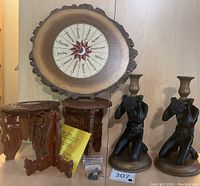 Photo showing two dark bronze kneeling male figure candlesticks holding candle holders, three wooden carved stands, and a round Wiccan craft wooden piece with symbolic text and agate edge.