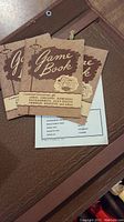Three brown and beige vintage game instruction booklets titled 'Game Book' covering chess, checkers, dominoes, backgammon, acey-ducey and others