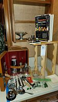 Full view of the vintage bar case open with various glassware and accessories on table, showing the book, wine rack, glasses, and utensils.