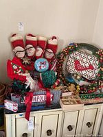Overview of the Christmas decorations including Santa stockings, wreath, ornaments, lights, North Pole bucket, and display rack on a cabinet