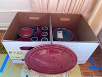 Overview of boxed dishware including plates, bowls, mugs, and another serving platter visible in front of box