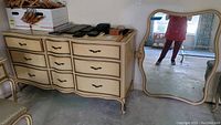Wide shot of the Drexel French Provincial dresser with nine drawers and matching mirror beside it showing overall style and condition.