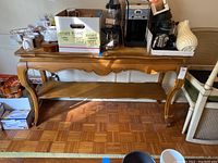 Full view of the wood entry table, showing the curved legs and carved apron, with kitchen items placed on top.