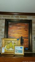 Full view of all three framed art pieces arranged against a brick wall, showing relative sizes and frame styles.