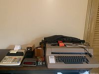 Wide view of all items arranged on table: typewriter, adding machine, electric pencil sharpener, mini clock, plastic sorter, and accessories.
