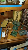 Top down photo showing wooden cross, metal candle holders, metal boxes, small wood box and large book-style case on wooden surface.