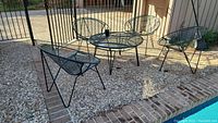 Full set with one round table and four mesh chairs on gravel patio