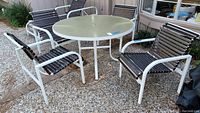 Outdoor set with round table and four chairs arranged on stone patio