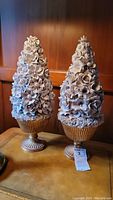 Two porcelain floral trees standing on urn bases, detailed with many porcelain flowers, beige color, approximately 19 inches tall.
