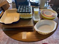 Full view of the lot showing ceramic casserole dish, glass food storage containers, Pyrex nested mixing bowls, ceramic trivet, and cutting boards.