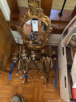 Top-down view of the gilded wall mirror and two wall sconces with wheat detail placed on the floor.